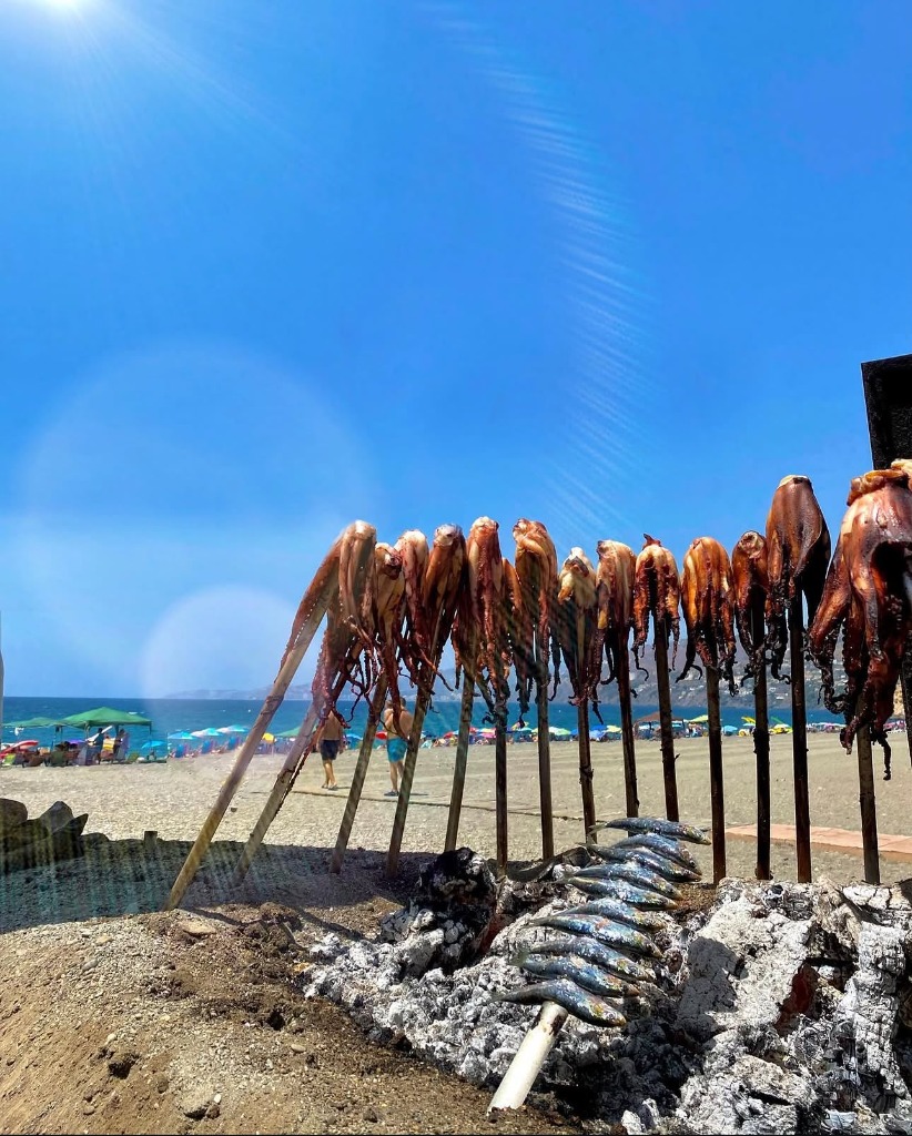 Espetos tradicionales de pulpo y sardinas al fuego en la playa de Salobreña