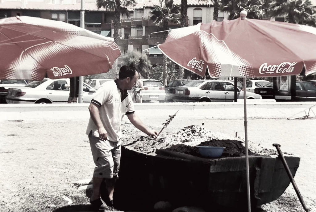 Emilio Rodríguez preparando espetos de sardinas en la barca frente a la playa